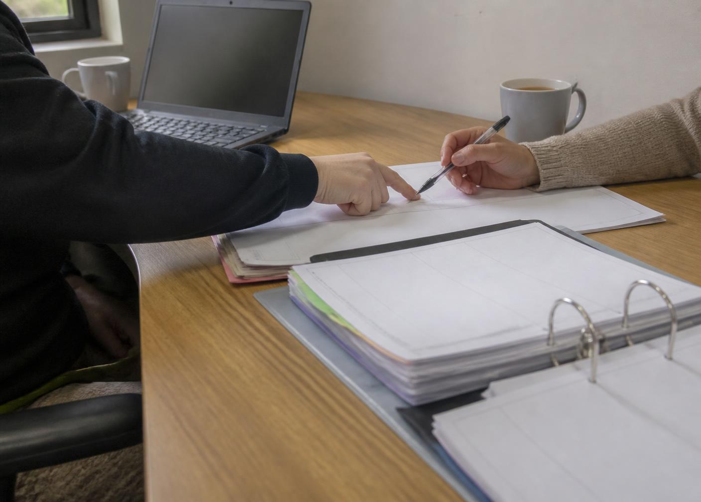 Members of the support team working together around a table with paperwork and notebooks